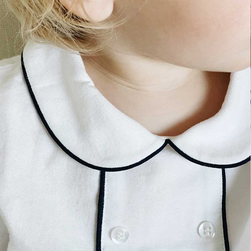 A sophisticated piped blouse in crisp white, showcasing meticulous tailoring and elegant design. This versatile garment effortlessly combines professionalism with a touch of modern flair, perfect for any fashion-forward wardrobe.
